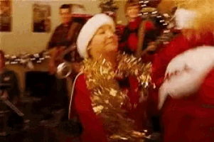 a woman in a santa hat is dancing with a man in a santa suit in a room .