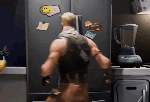 a man standing in front of a refrigerator with a blender in the kitchen .