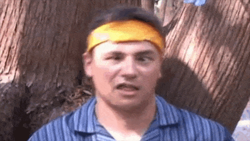 a man wearing a blue shirt and a yellow headband is making a funny face .