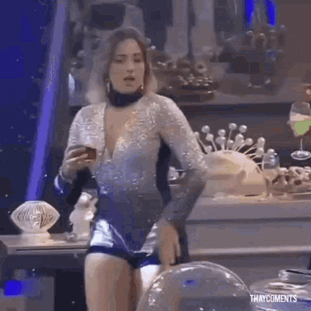 a woman in a bodysuit is standing in front of a table with a glass of wine .