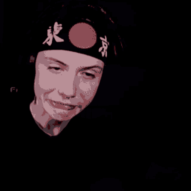 a man wearing a headband with a red circle on it is making a funny face .