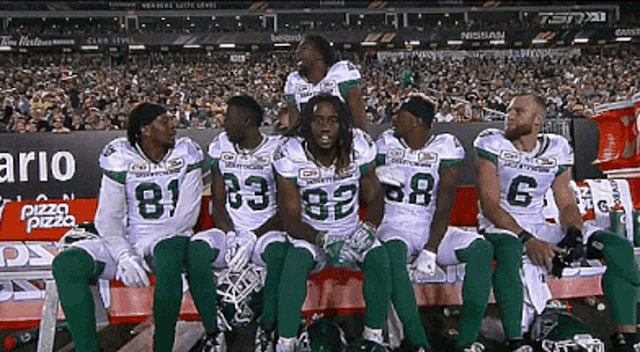 a group of football players are sitting on a bench with one wearing a number 6 jersey