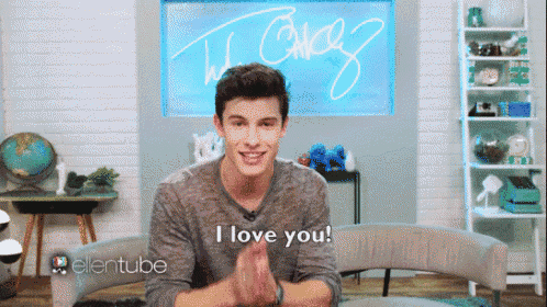 a young man is sitting in front of a sign that says i love you