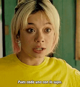 a woman in a yellow shirt is making a funny face and says pues cada uno con lo suyo .
