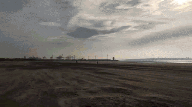 a beach with a cloudy sky and a few people