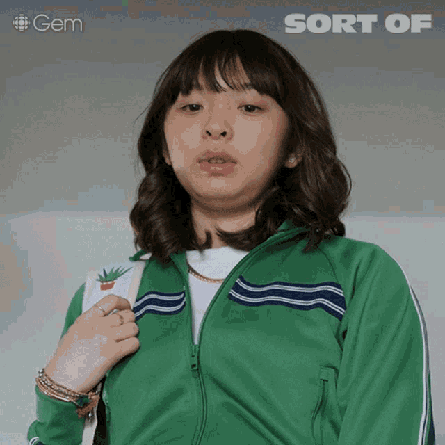 a girl in a green jacket is holding a backpack and the word sort of is above her