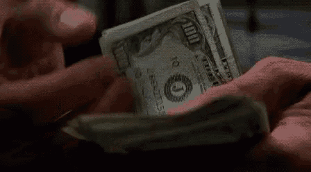 a person is holding a stack of dollar bills in their hands .
