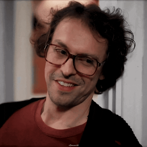a close up of a man wearing glasses and a red shirt