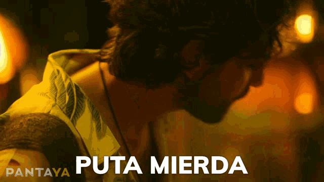 a man in a yellow shirt is standing in front of a sign that says puta mierda
