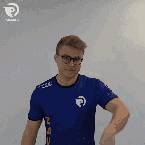 a man wearing glasses and a blue shirt that says origen