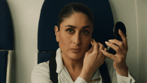 a woman with the name kareena on her shirt is looking at herself in the mirror