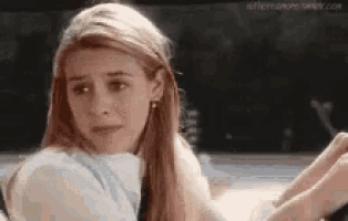 a woman with long blonde hair is sitting in a car and looking at the camera .