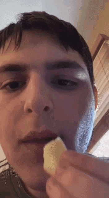 a young man is eating a piece of cheese