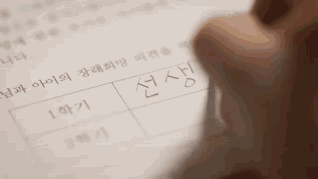 a close up of a person writing on a piece of paper in korean .