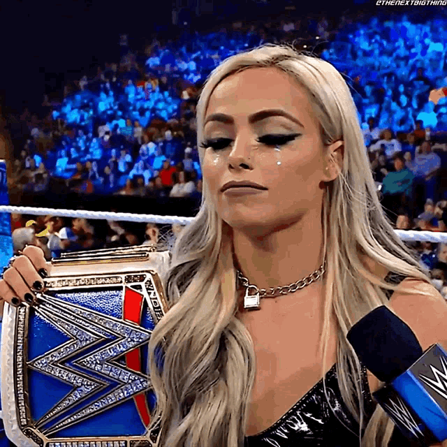 a woman is holding a wrestling championship belt and crying while talking into a microphone