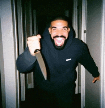 a man in a black hoodie is holding a large knife in a hallway .