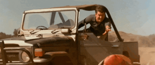 a man is getting out of a toyota truck in the desert