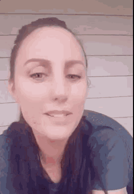 a close up of a woman 's face with her eyes closed and a blue shirt on .