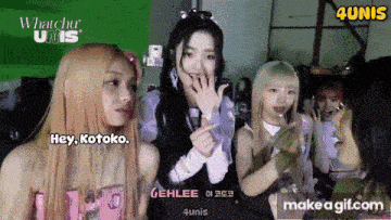 a group of girls are standing next to each other and one of them is making a heart shape with her hands .