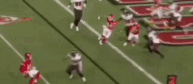 a blurry picture of a football game with a referee in the foreground .