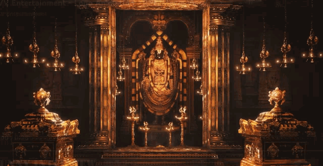 a gold temple with a statue of a deity and candles hanging from the ceiling
