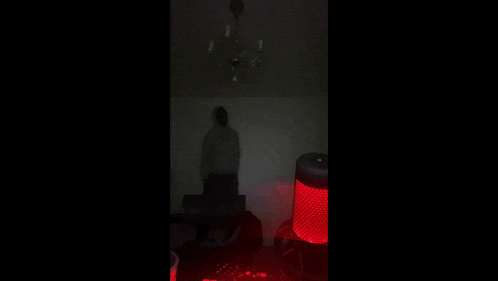 a person in a hoodie stands in a dark room