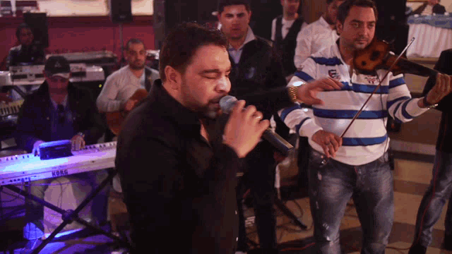 a man singing into a microphone while another man plays the violin