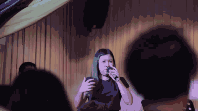 a woman sings into a microphone in front of a crowd of people