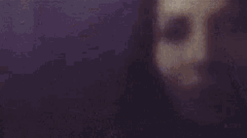 a close up of a woman 's face in a dark room with a blurred background .