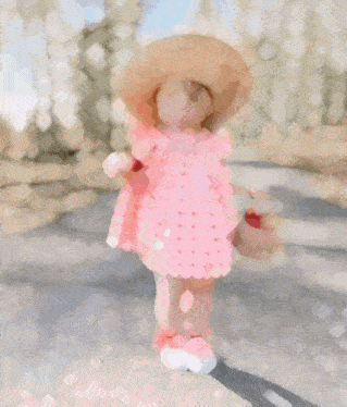 a little girl wearing a straw hat and a pink dress holds a basket of strawberries