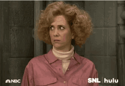 a woman with curly hair is wearing a pink shirt and a white turtleneck sweater .