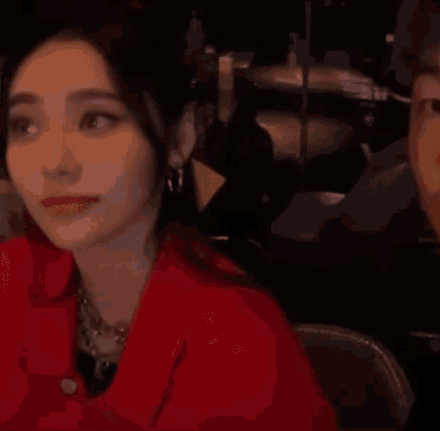a woman in a red jacket is sitting next to a man in a chair and looking at the camera .