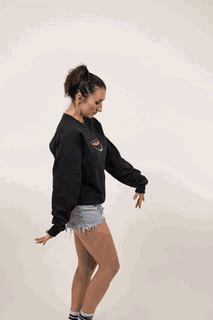 a woman wearing shorts and a black sweatshirt with a bowl on the front