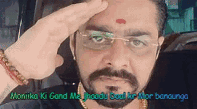 a man with glasses and a red dot on his forehead is saluting .