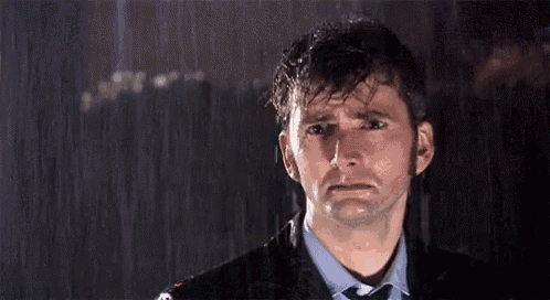 a man in a suit and tie is crying in the rain at night .