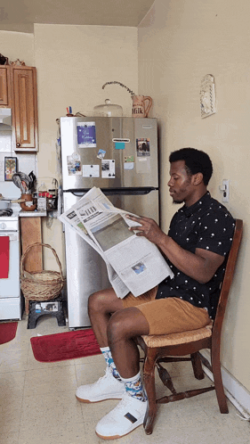 a man is reading a newspaper in front of a refrigerator