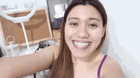 a woman in a purple bra is smiling and taking a selfie in front of a mirror .