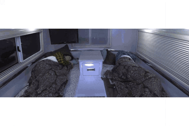 two people sleeping in a small room with a nightstand