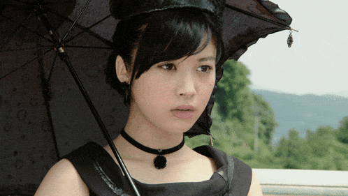 a woman wearing a choker and holding an umbrella looks at the camera