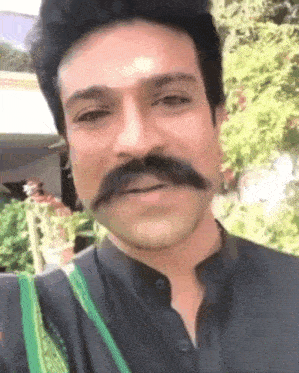 a man with a mustache is smiling and wearing a black shirt .