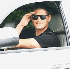 a man wearing sunglasses is driving a car