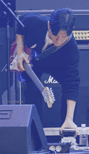 a man playing a guitar in front of a marshall amp