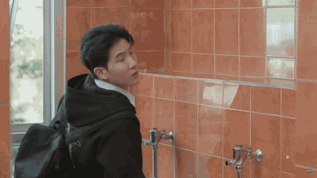 a man with a backpack stands in a bathroom