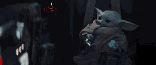 a baby yoda is sitting in a chair with a belt around his waist