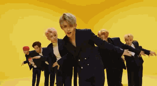 a group of men are dancing in front of a yellow background .