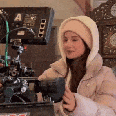 a woman in a hooded jacket is holding a camera .