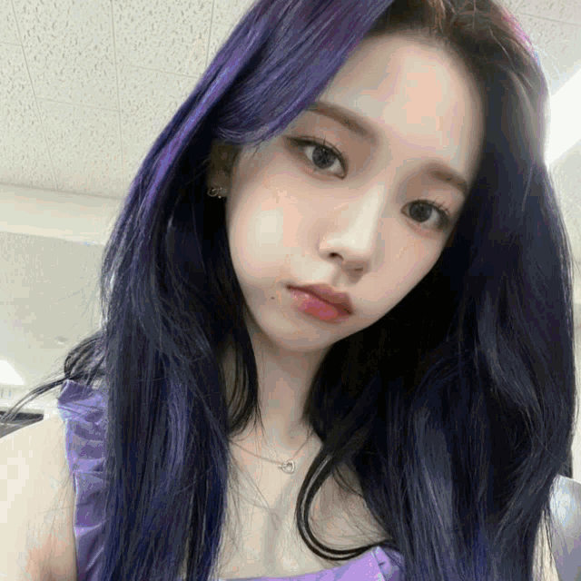 a woman with purple hair is wearing a purple tank top