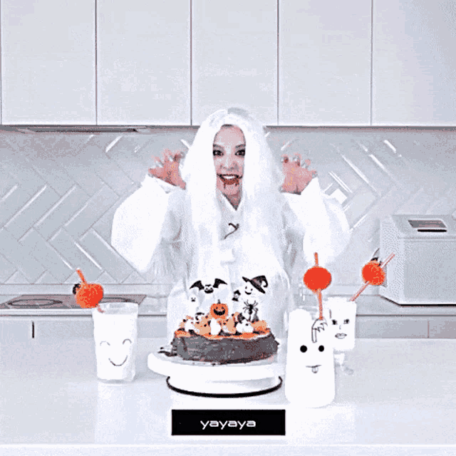 a woman in a ghost costume stands in front of a cake and a sign that says " yayaya "