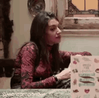a woman is sitting at a table with a book in front of her ..