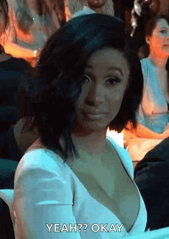 a woman in a white dress is sitting in a crowd and making a face .